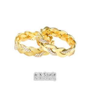 Puede incluir: Dos anillos trenzados de oro con pequeños diamantes engastados en la banda. Los anillos están entrelazados y son un estilo popular para las alianzas de boda.