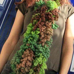 May include: A brown and green crocheted scarf with a fluffy texture. The scarf is worn by a person with long brown hair.