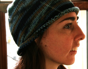 May include: A knitted beanie hat with horizontal stripes in shades of blue, black, and brown. The hat has a folded brim and is made of a soft, textured yarn. The hat is a casual accessory.
