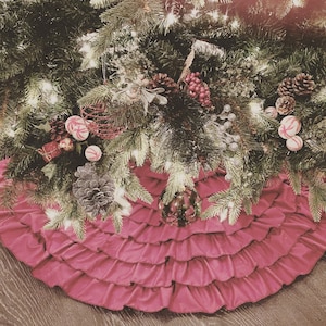 May include: A pink ruffled Christmas tree skirt with a green Christmas tree decorated with ornaments, candy canes, and pine cones.