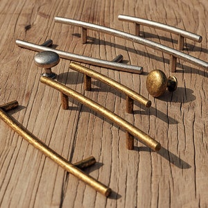 Puede incluir: Surtido de herrajes decorativos para armarios en acabados dorado y plateado. Los herrajes incluyen varios estilos de tiradores de cajones y pomos de armario.