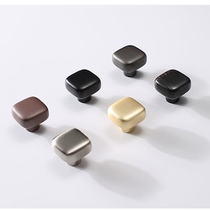 May include: Six square cabinet knobs in different finishes: black, brown, gold, silver, brushed nickel, and dark bronze.