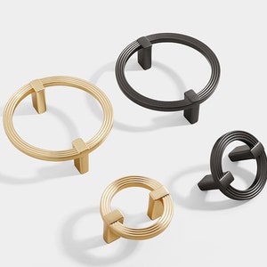 Può includere: Quattro pomelli rotondi per armadio con un design a cerchi concentrici. Due pomelli sono dorati e due sono neri.