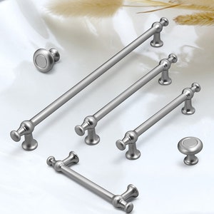 Puede incluir: Un juego de seis pomos y tiradores de armario plateados. Los pomos son redondos y tienen un diseño sencillo. Los tiradores son rectangulares y tienen una forma ligeramente curvada. Los tiradores están disponibles en tres tamaños diferentes.