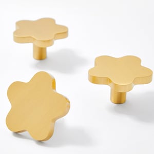 Może przedstawiać: Trzy złote, kwiatowe gałki meblowe z wykończeniem szczotkowanym.