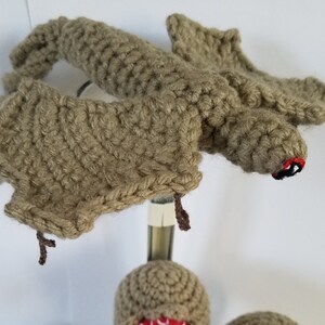 May include: Four crocheted plush toys in the shape of the creature from the movie "Stranger Things". The creature is brown with red and white eyes. One of the creatures is flying.