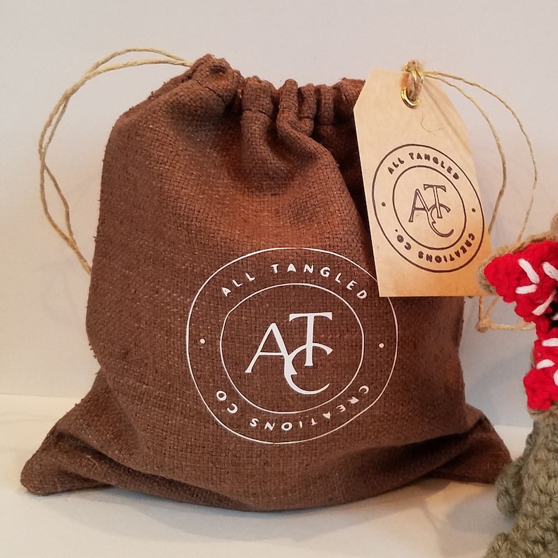 May include: A brown burlap drawstring bag with a white logo that says "All Tangled Creations AT Co.". The bag is tied with twine and has a brown paper tag with the same logo.