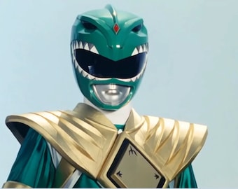 May include: A green Power Ranger helmet with a gold chest plate and shoulder pads. The helmet has a large, toothy mouth and a diamond-shaped gem on the forehead.