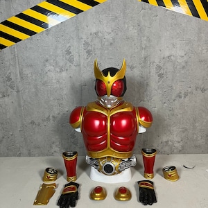 May include: A red and gold action figure with a helmet and a belt. The figure is disassembled and laid out on a white surface. The figure includes a chest piece, two arms, two legs, two gloves, two wrist pieces, and two shoulder pieces.