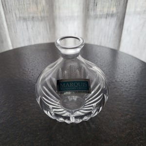 Könnte beinhalten: Klarer Kristallvase von Marquis Waterford mit rundem Körper und schmalem Hals. Die Vase hat ein strukturiertes, geripptes Design und ein rechteckiges Etikett mit der Aufschrift "MARQUIS WATERFORD CRYSTAL CZECH REPUBLIC."