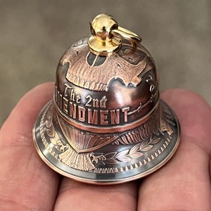 May include: A copper and gold bell with a detailed design featuring an eagle, a wreath, and the words "The 2nd Amendment".
