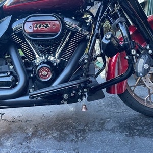 May include: Close-up of a red Harley Davidson motorcycle with a black engine and a chrome air filter. The motorcycle has a black bell hanging from the bottom of the frame.
