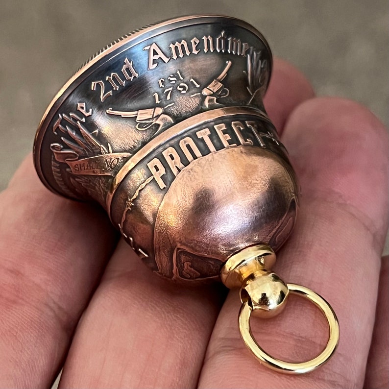 May include: A copper bell with a gold ring. The bell is engraved with the words "The 2nd Amendment Est 1791" and "Protect".
