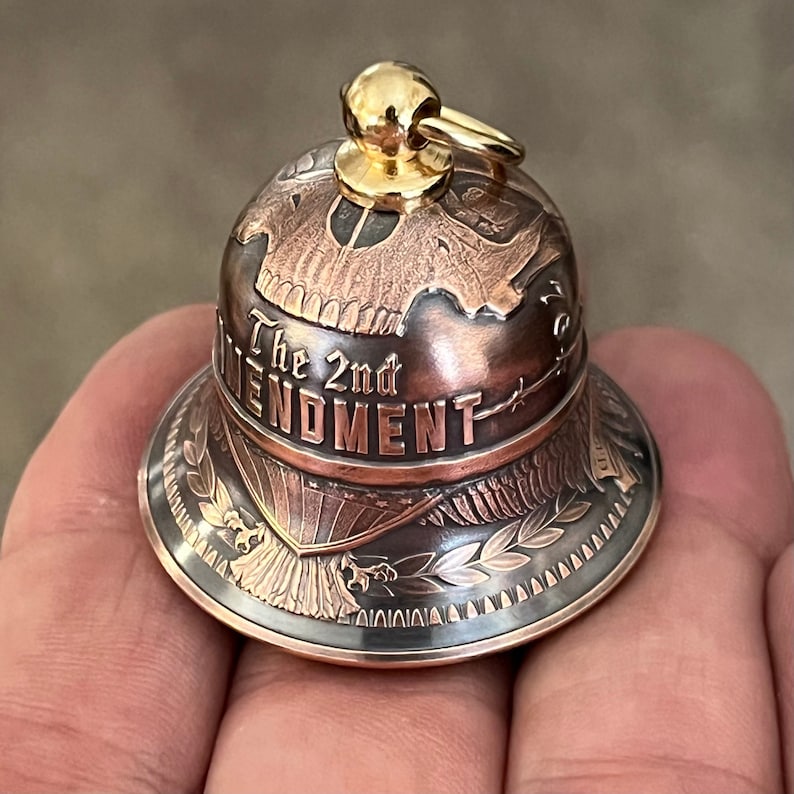 May include: A copper and gold bell with a detailed design featuring an eagle, a wreath, and the words "The 2nd Amendment".