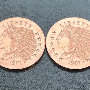 May include: Two copper-colored round coins featuring the profile of a person wearing a feathered headdress. The word LIBERTY is arched at the top, and the year 1901 is printed at the bottom. Thirteen stars are arranged along the coin edge.