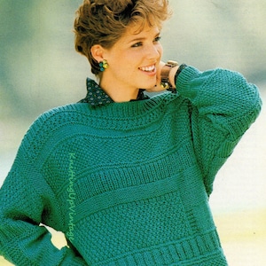 May include: A teal blue knitted jumper with a textured pattern. The jumper has a round neckline and long sleeves.
