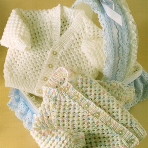 May include: Two knitted baby cardigans, one white and one with a multi-coloured pattern. Both cardigans have a button fastening and a delicate openwork stitch.