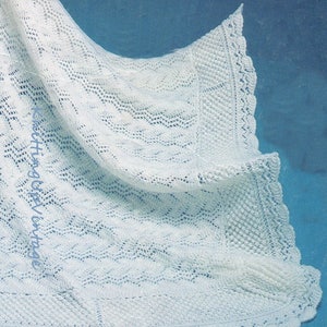 May include: A white crocheted baby blanket with a delicate lace border. The blanket is made with a lacy stitch pattern and has a scalloped edge.
