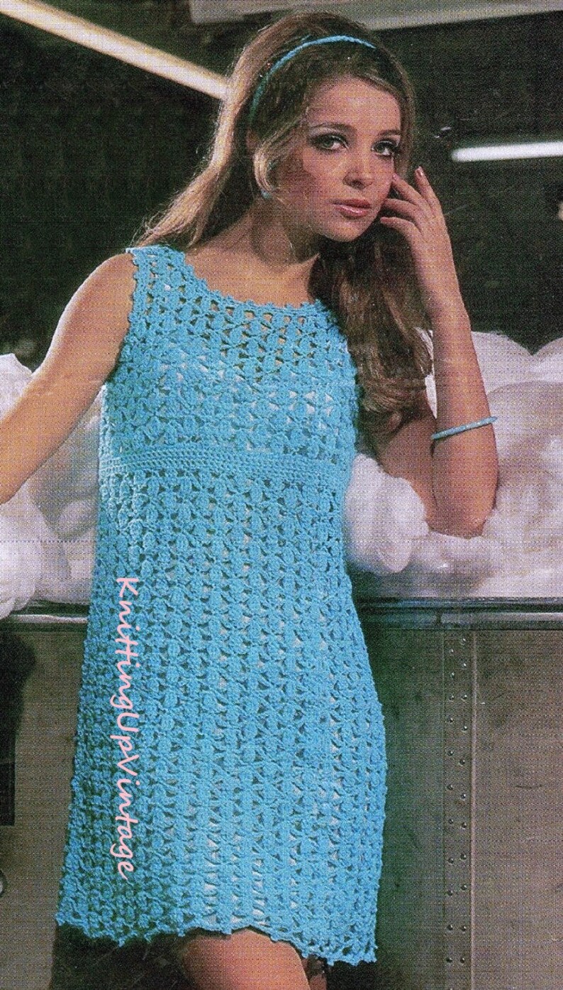 May include: A blue crochet dress with a sleeveless design. The dress has a delicate, openwork pattern and a slightly flared skirt.