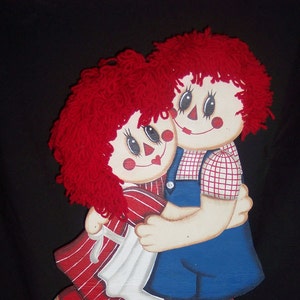 Könnte beinhalten: Holzfiguren von zwei Puppen, die sich umarmen. Die Puppen haben rote Wollhaare, bemalte Gesichter und sind in rot, weiß und blauen Outfits gekleidet. Der Text "https://etsy.com/shop/happyhollowcreation" befindet sich unten.