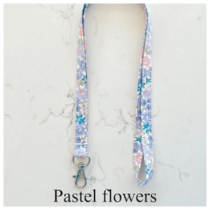 Peut inclure: Un cordon blanc avec un motif floral pastel et un fermoir argent&eacute;. Le cordon mesure environ 45 cm de long.