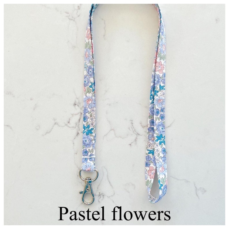 Peut inclure: Un cordon blanc avec un motif floral pastel et un fermoir argent&eacute;. Le cordon mesure environ 45 cm de long.