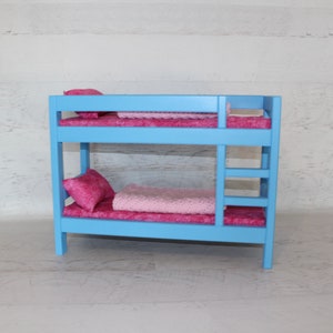 May include: A light blue wooden bunk bed with pink bedding and pillows. The bed is made of wood and has a ladder on the side.