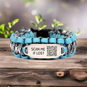 Puede incluir: Una pulsera de paracord azul, negro y blanco con una hebilla negra. La pulsera tiene una etiqueta blanca con el texto "SCAN ME IF LOST" y un código QR.