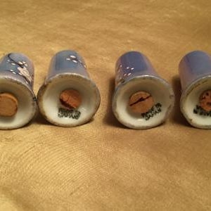 May include: Four blue and white salt and pepper shakers with cork tops. The shakers have a floral design and are made of ceramic.