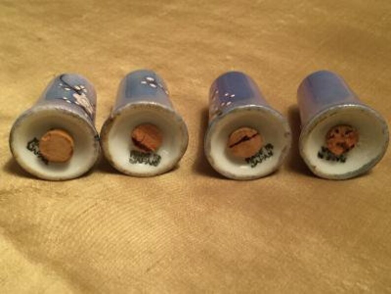 May include: Four blue and white salt and pepper shakers with cork tops. The shakers have a floral design and are made of ceramic.