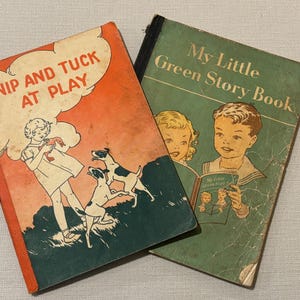 May include: Two vintage children's books. One book has an orange cover with the title "Nip and Tuck at Play" and an illustration of a child and dogs. The other book is green and titled "My Little Green Story Book".