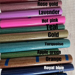 May include: A close-up of a variety of glitter heat transfer vinyl rolls in different colours, including magenta, red, rose gold, lavender, hot pink, teal, gold, turquoise, apple green, orange, royal blue, and blue.