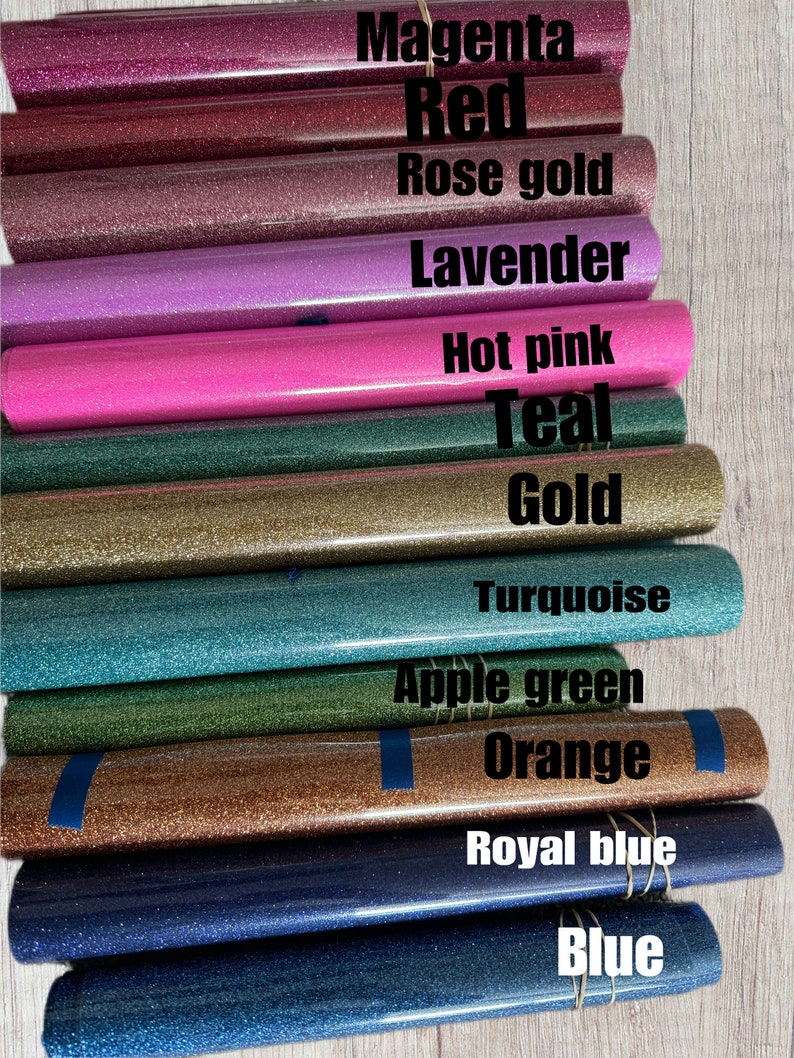 May include: A close-up of a variety of glitter heat transfer vinyl rolls in different colours, including magenta, red, rose gold, lavender, hot pink, teal, gold, turquoise, apple green, orange, royal blue, and blue.
