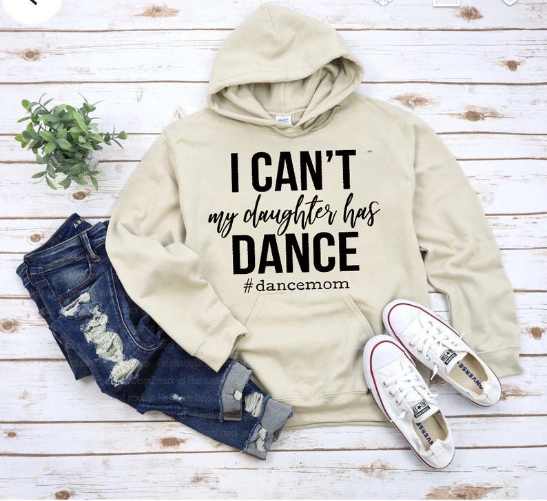May include: A beige hoodie with a black graphic that says "I can't my daughter has dance #dancemom".