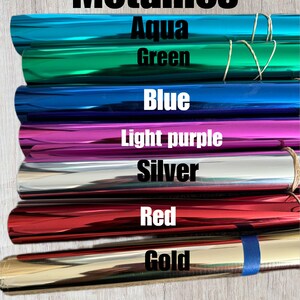 May include: A stack of seven metallic rolls of vinyl in various colours, including aqua, green, blue, light purple, silver, red, and gold. The rolls are labelled with their respective colours.
