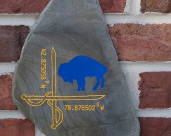 Slate wall hanging with latitude and longitude of center ice of Sabres team with a standing blue buffalo