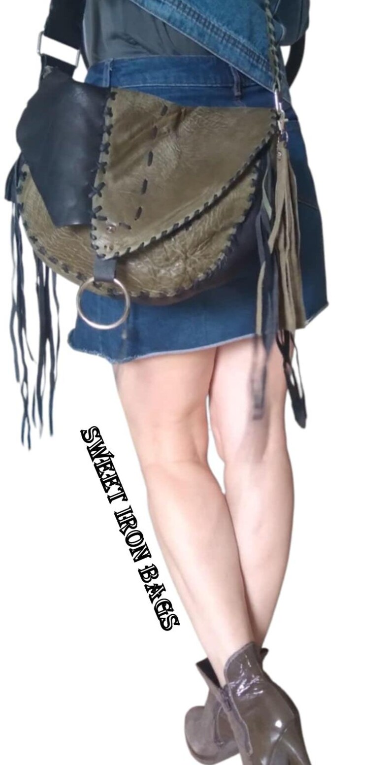 May include: A green and black leather crossbody bag with fringe details and a silver ring on the strap. The bag is worn by a person wearing a denim skirt and boots. The text "SWEET IRON BAGS" is visible on the image.