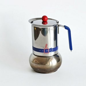May include: A silver and blue stovetop espresso maker with a red knob on the lid. The maker has a blue band with the letter "R" and a blue and red design.