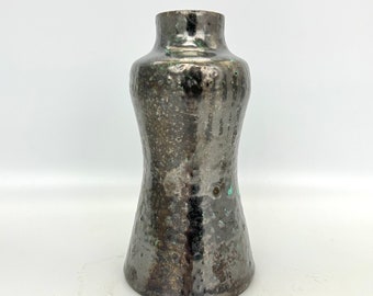 May include: A small, dark gray ceramic vase with a textured, metallic finish. The vase has a slightly flared opening and a rounded base.