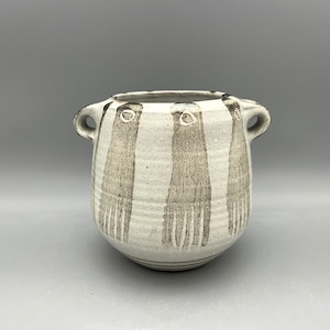 May include: A white ceramic pot with two handles and a brown, abstract design. The pot has a rounded shape and a slightly flared rim.