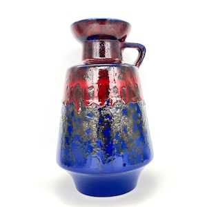 May include: A blue and red ceramic vase with a textured glaze. The vase has a wide mouth and a handle.