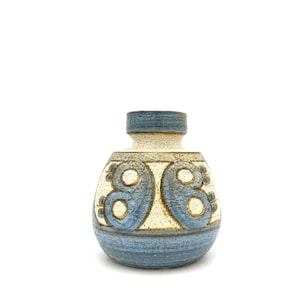 May include: A small ceramic vase with a rounded body and a short neck. The surface features a textured, speckled cream-colored base with blue painted abstract circular patterns and a solid blue band around the base and the rim of the opening.