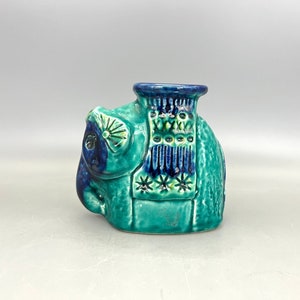 Puede incluir: Una figurita de elefante de cerámica con esmalte azul y verde. El elefante tiene una silla de montar estampada y una cara detallada.
