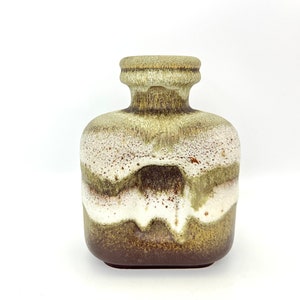 May include: A brown, white and green ceramic vase with a textured surface. The vase has a wide, square base and a narrow neck.