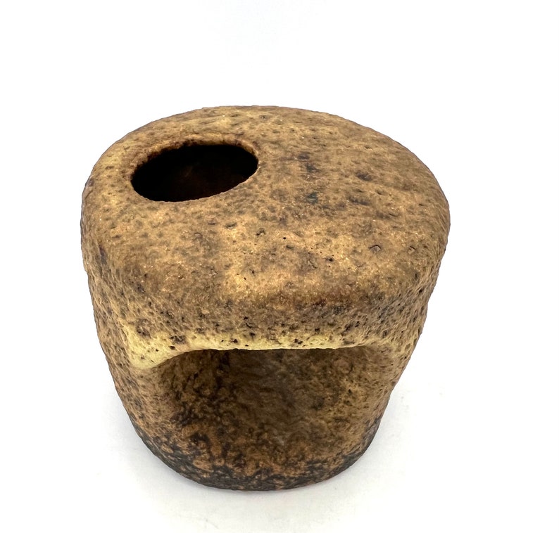 K&ouml;nnte beinhalten: Ein brauner Keramiktopf mit einer rauen, strukturierten Oberfl&auml;che. Der Topf hat eine runde &Ouml;ffnung oben und eine kleinere &Ouml;ffnung an der Seite.
