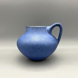 May include: A blue ceramic pitcher with a textured surface and a single handle.