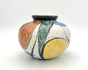 May include: A small, round ceramic vase with a textured white glaze and abstract geometric designs in black, brown, yellow, blue, and green.