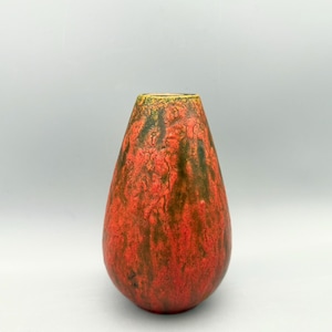Può includere: Un vaso in ceramica a forma di goccia con una superficie strutturata. Il vaso presenta una vivace tavolozza di colori rosso, marrone e giallo. Ha una base ampia e si assottiglia verso l'alto, creando un design unico e accattivante.