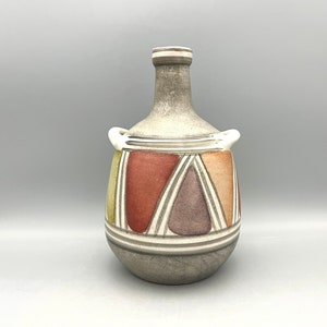 May include: A gray ceramic vase with a geometric design in shades of red, orange, yellow, and purple. The vase has two handles and a narrow neck.