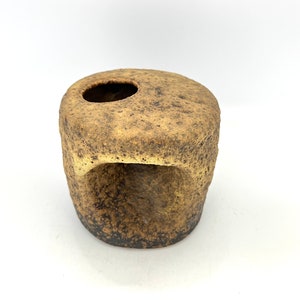 K&ouml;nnte beinhalten: Eine kleine, braune Keramikvase mit einer rauen, strukturierten Oberfl&auml;che. Die Vase hat zwei &Ouml;ffnungen, eine oben und eine an der Seite.